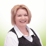 Eine lächelnde Frau mit kurzen, hellblonden Haaren, die ein weißes Hemd mit Kragen und eine dunkelgraue Weste trägt, posiert vor einem Hintergrund mit weißem und hellgrünem Farbverlauf. Eine lächelnde Frau mit kurzen, hellblonden Haaren, die ein weißes Hemd mit Kragen und eine dunkelgraue Weste trägt, posiert vor einem Hintergrund mit weißem und hellgrünem Farbverlauf.